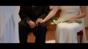 Novia agarra la mano del novio. Están sentados en un sillón en la iglesia. Durante la ceremonia.